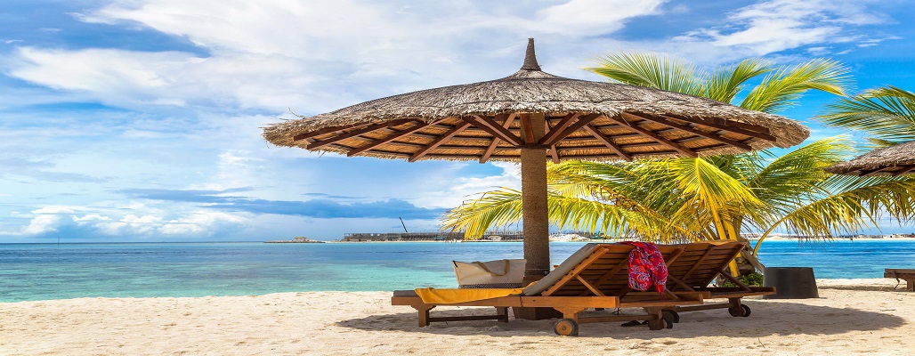 MALDIVES - JUNE 24, 2018: Wooden sunbed and umbrella on tropical beach in the Maldives at summer day